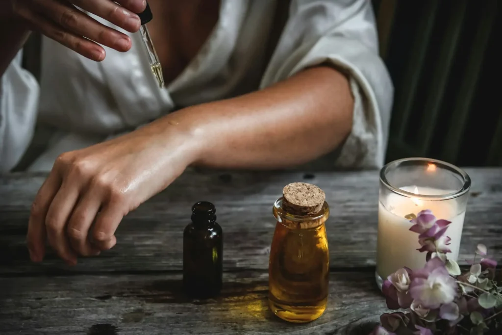 Vela votiva acesa ao lado de óleo corporal, simbolizando saúde, beleza e bem-estar.