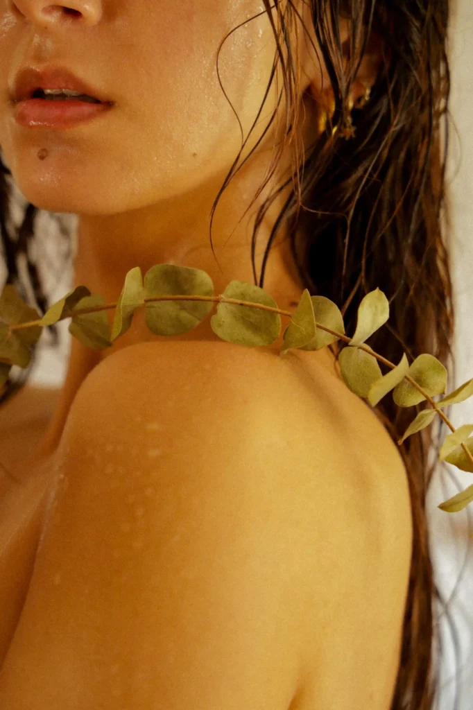 um close up de uma mulher usando um colar com folhas sobre ele