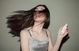 Mulher segurando frasco spray de cuidados capilares, ideal para rotina de cronograma capilar em cabelos oleosos